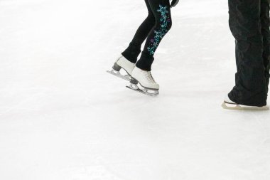 Artistik patinajda bir artistik patinajcı ve koçunun ayakları görülüyor..