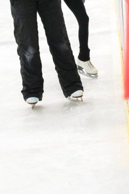 Artistik patinajda bir artistik patinajcı ve koçunun ayakları görülüyor..