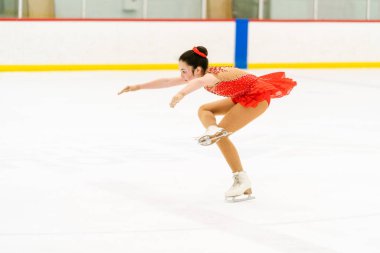 Genç kız buz pateni pistinde artistik patinaj yapıyor..