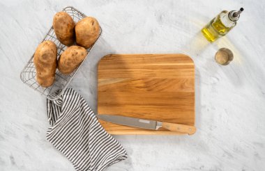 Düz yatıyordu. Fırında pişirmek için ahşap kesme tahtasıyla russet patateslerini dilimlemek..