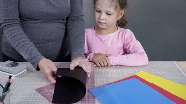 İnşaat kağıdından el yapımı Babalar Günü kartı yapan küçük bir kız..