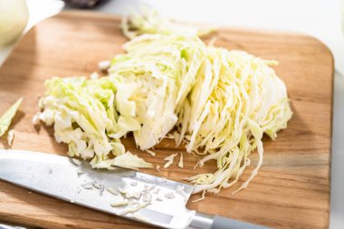 Ağaç kesme tahtasında yeşil lahana öğütüyorum..