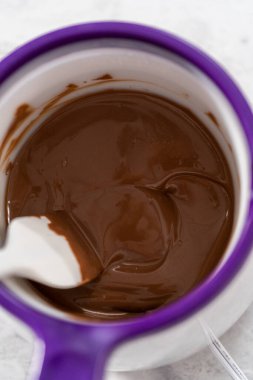 Çikolata erir, şeker tenceresinde erir. Gurme mini çikolatalar hazırlamak için çikolata serpiştirir..