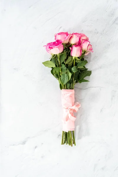 ピンク色のバラの花束は 具体的な背景にピンクのリボンとピンクの包装紙に包まれました — ストック写真