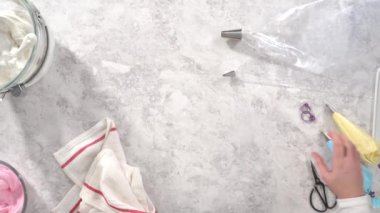 Tek boynuzlu at meringue kurabiyesi pişirmek için metal uçlu boru torbalarına krema karışımı aktarılıyor..