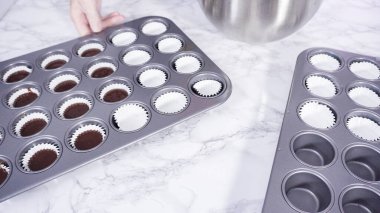 Adım adım. Mini çikolatalı kekler pişirmek için kek hamurunu mini kek kuyruklarına karıştırmak..