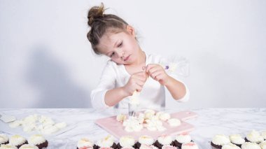 Adım adım. Küçük kız kesme tahtasına tereyağı kreması sürme alıştırması yapıyor.