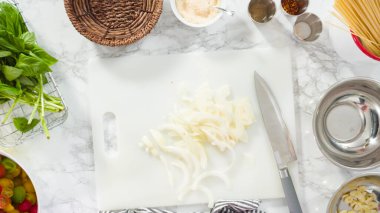 Düz yatıyordu. Adım adım. Tek demlik makarna tarifi yapmak için beyaz bir kesim tahtasıyla sebze kesmek..