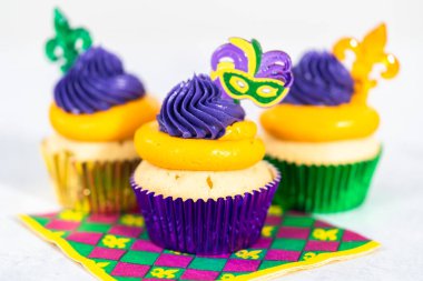 Mardi Gras vanilyalı kekler folyo kaplarda ve İtalyan tereyağlı kremayla süslenmiş..