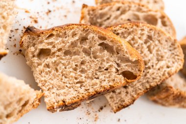 Beyaz bir kesme tahtasının üzerinde taze pişmiş ekşi ekmek dilimliyorum..