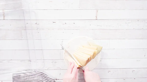 平置きだ 一歩ずつ キッチンナイフで白いまな板の上でグルメチーズをスライス — ストック写真