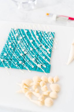 Çiseleyen beyaz çikolata ve üzerine beyaz inci şekeri serpiştiren mini çikolata ozanı.