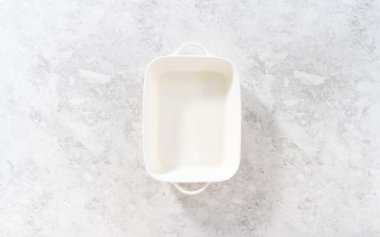 Düz yatıyordu. Ekmek pudingi pişirmek için beyaz güveç tabağı yağlıyorum..