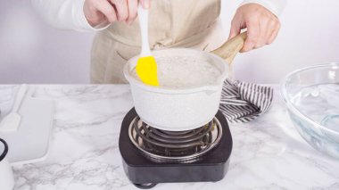 Adım adım. Küçük elektrikli ocağın üzerinde küçük bir tencerede karamelize şeker.