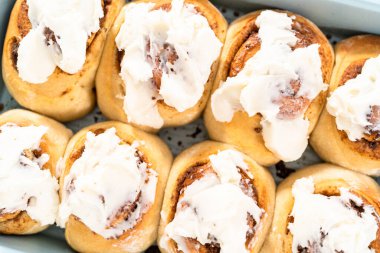 Taze pişmiş tarçınlı rulo, beyaz kremalı, mavi bir tavada..