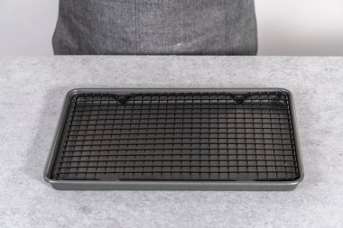 Gri arkaplanda tel askısı olan boş fırın kağıdı.