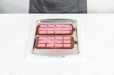 Mini pembe çikolatalar yapmak için silikon çikolata kalıbını erimiş çikolatayla dolduruyorum..