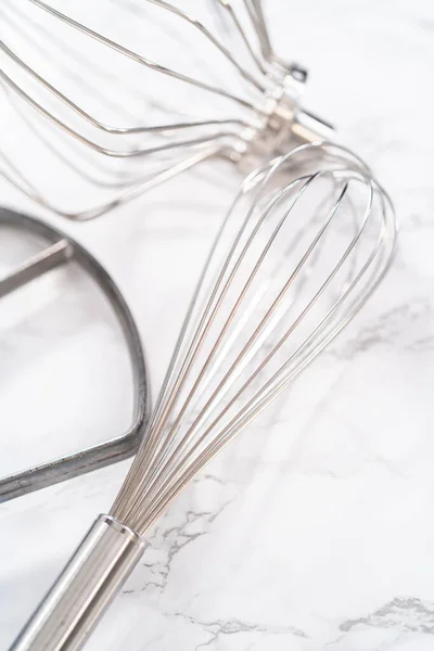 Close-up view. Variety of blending whisks on a marble countertop.