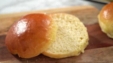 Odun kesme tahtasının üzerinde taze pişmiş çörekleri dilimliyorum..