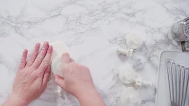 Mermer tezgahın üzerindeki beyaz fondanla kar tanelerini keserek..