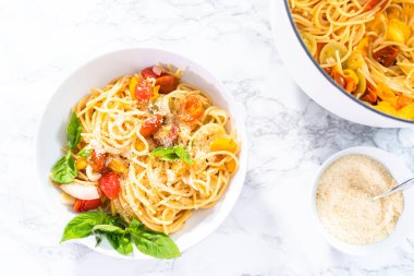 Kiraz domatesli vejetaryen makarna ve beyaz tabakta taze fesleğen..