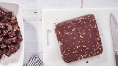 Düz yatıyordu. Adım adım. Beyaz kesim tahtasında ev yapımı macadamia şekerlemesi kesiyorum..