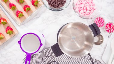 Düz yatıyordu. Adım adım. Çikolata parçacıkları eriyen kaplarda eriyor..