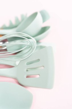 Pembe arka planda ahşap saplı yeni mavi silikon mutfak aletleri..