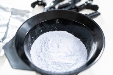 Siyah plastik bir kasede beyaz arka planda saç boyası tozu..