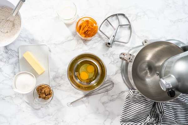 Flat lay. Ingredients to bake pumpkin spice cupcake on a marble countertop.