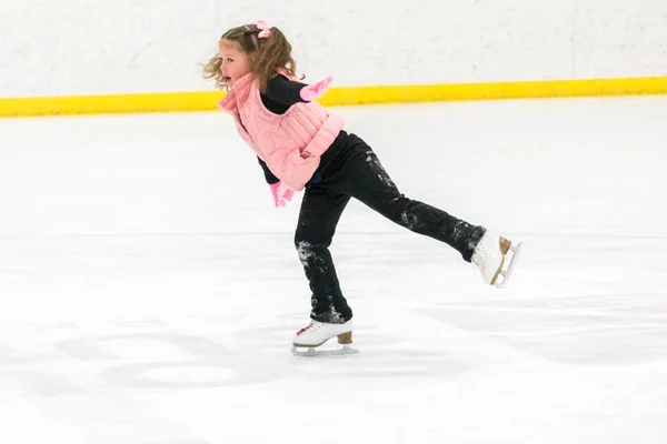 小さな女の子練習フィギュアスケートムーブオンザ屋内アイスリンク — ストック写真