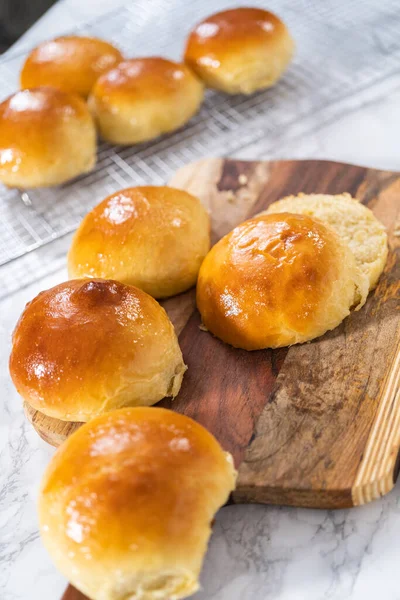 Odun kesme tahtasının üzerinde taze pişmiş çörekleri dilimliyorum..