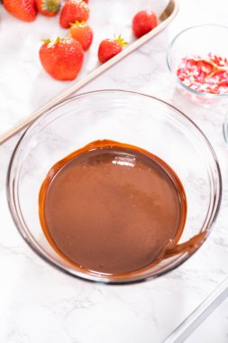 Çikolata kaplı çilekleri hazırlamak için cam bir kasede erimiş çikolata..