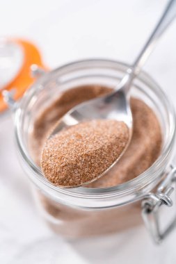 Mermer yüzeyde cam bir taş kavanozunda tarçın şekeri.