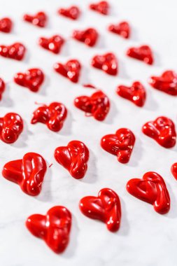 Erimiş çikolatayı parşömen kağıdının üzerine dökerek çikolatadan kalp yapmak..