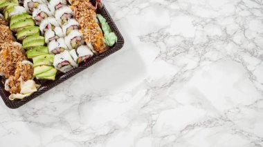 Düz yatıyordu. Önceden paketlenmiş suşi ve suşi çeşitleri plastik tepside..