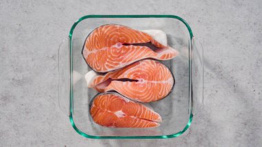 Izgara için cam bir tabakta marine edilmiş somon bifteği..