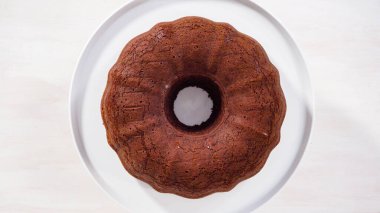 Adım adım. Düz yatıyordu. Beyaz pasta standında taze pişmiş çikolatalı kek..