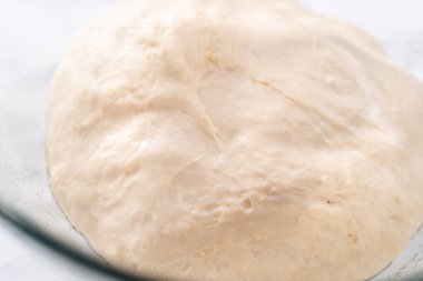 Tarçınlı tatlı pizzası hazırlamak için cam bir kasede pizza hamuru yetiştiriyorum..