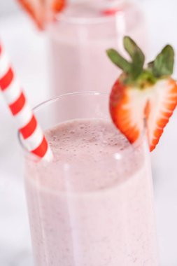 Taze taze çilek ve kağıt kamışla süslenmiş sağlıklı bir kahvaltı muzlu smoothie..