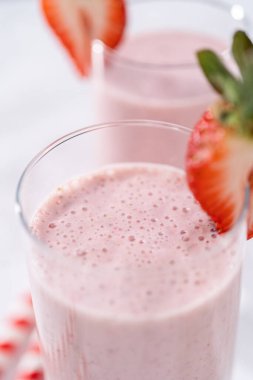 Taze taze çilek ve kağıt kamışla süslenmiş sağlıklı bir kahvaltı muzlu smoothie..