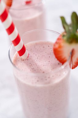 Taze taze çilek ve kağıt kamışla süslenmiş sağlıklı bir kahvaltı muzlu smoothie..