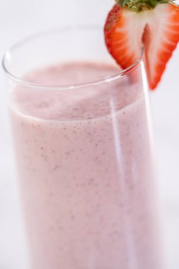 Taze taze çilek ve kağıt kamışla süslenmiş sağlıklı bir kahvaltı muzlu smoothie..