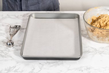 Çikolatalı zencefilli bir adamla yumurta likörü pişirmek için parşömen kağıdıyla kaplanmış hamur hamurunu hamur kepçesiyle pişirmek..