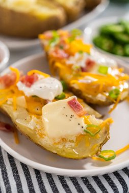 Fırında pişmiş patates. Tereyağı, ekşi krema, peynir ve pastırma parçalarıyla süslenmiş büyük fırında patates..