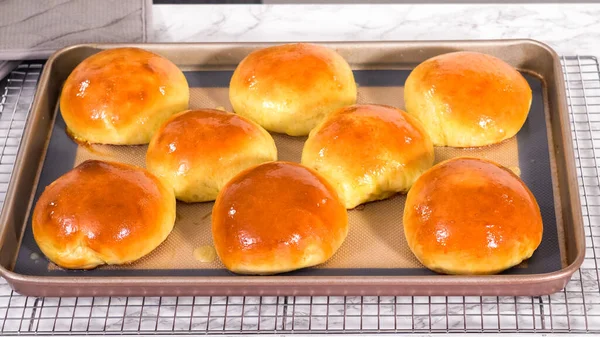 Step by step. Freshly baked brioche buns on a baking sheet with a silicone mat.
