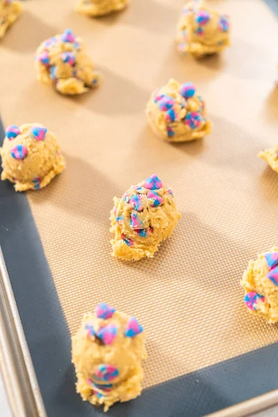 Chilled cookie dough scoops on the baking sheet to bake unicorn chocolate chip cookies.