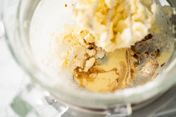 Büyük bir bardaktaki malzemeleri karıştırıyorum. Yumurta likörü kreması yapmak için mutfak mikserini karıştırıyorum..