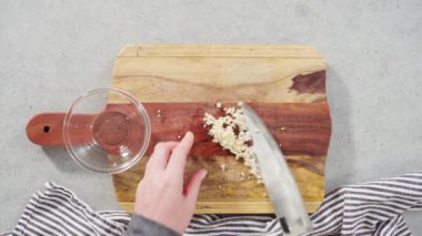 Ağaç kesme tahtasıyla organik sarımsak kesmek.