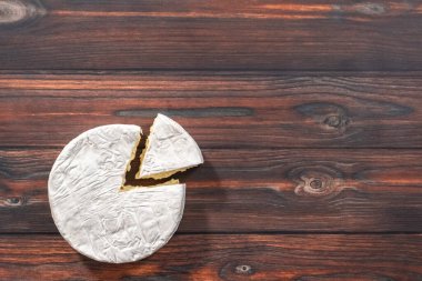 Düz yatıyordu. Dilimlenmiş Fransız krem peyniri, koyu ahşap arka planda..